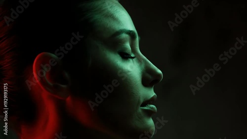 Profile Portrait of Woman with Closed Eyes in Red and Green Lighting on Dark Background