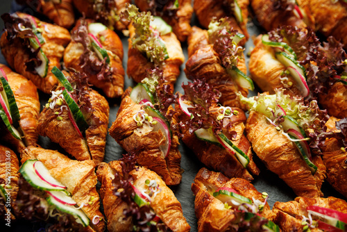 Mini croissant sandwiches with lettuce and radish on a catering platter