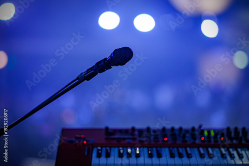 Microphone and electronic keyboard on stage with blue bokeh background