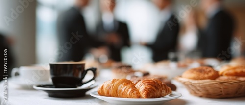 Business coffee break with fresh croissants and coffee cup on table. Blurred group of businessmen in suits networking and talking in the background during a corporate conference. Panoramic banner.