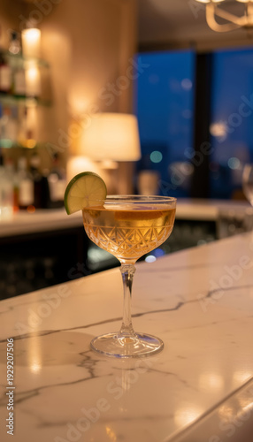 Cocktail drink with lime garnish on marble bar counter in a luxurious setting. Evening beverage serving