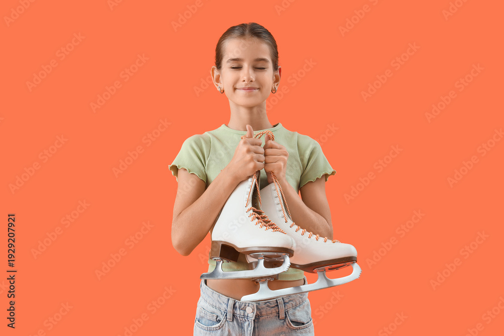 Fototapeta premium Dreamy teenage girl with ice skates on orange background
