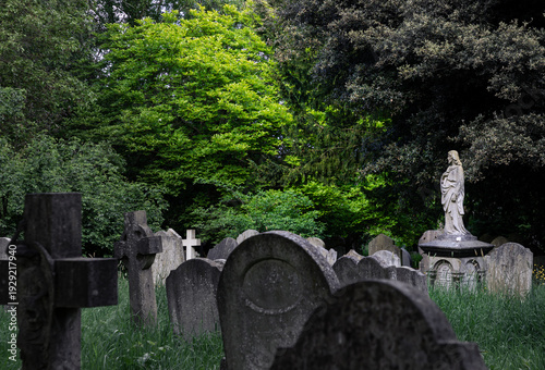 Foto A statue of Jesus stands sentinel over a serene, overgrown section of London's historic Highgate Cemetery