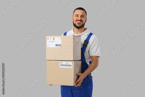 Delivery man with parcel boxes on light background