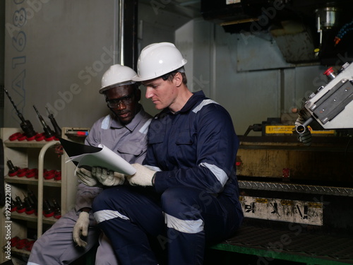 Industrial engineers discussing work documents in manufacturing factory