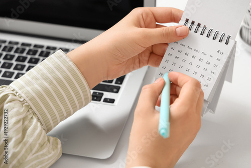 Fotografija Female hands marking day on flip calendar at table in office, closeup