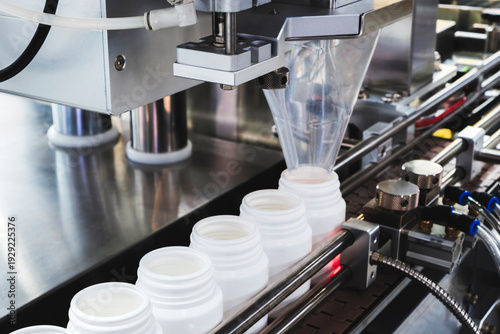 Φωτογραφία filling and packaging machine at pharmaceutical factory fills white plastic jars with tablets or ampoules containing dietary supplements