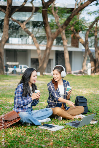 Asian university students studying together outdoors using laptop and smartphone, enjoying digital learning, teamwork and modern campus lifestyle
