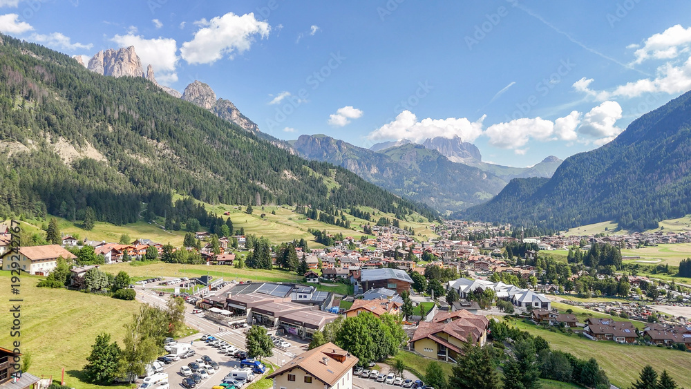 Fototapeta premium Aerial, bird view of Vigo di fassa, Val di fassa valley, Trentino, a town in the Italian dolomites. Sunny summer day. Mountain landscape. Dolomites. Beautiful travel destination.
