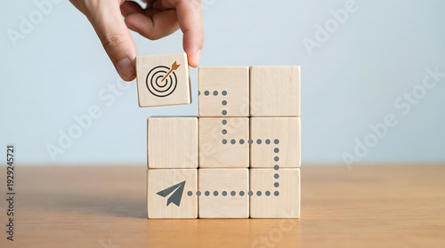 Hand placing target cube on path of blocks, planning business strategy and goal achievement