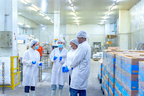 Photos Workers discuss safety protocols in food processing facility near noon on a week