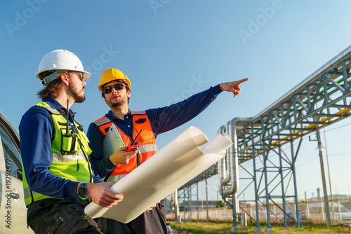Cuadro en lienzo Two workers review blueprints at a construction site during the day with a clear