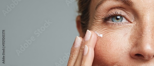 Mature woman applying anti-aging cream to wrinkles under eye