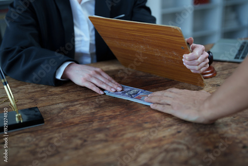 Photos Two people exchange cash over a wooden desk in a clandestine backroom deal, evok