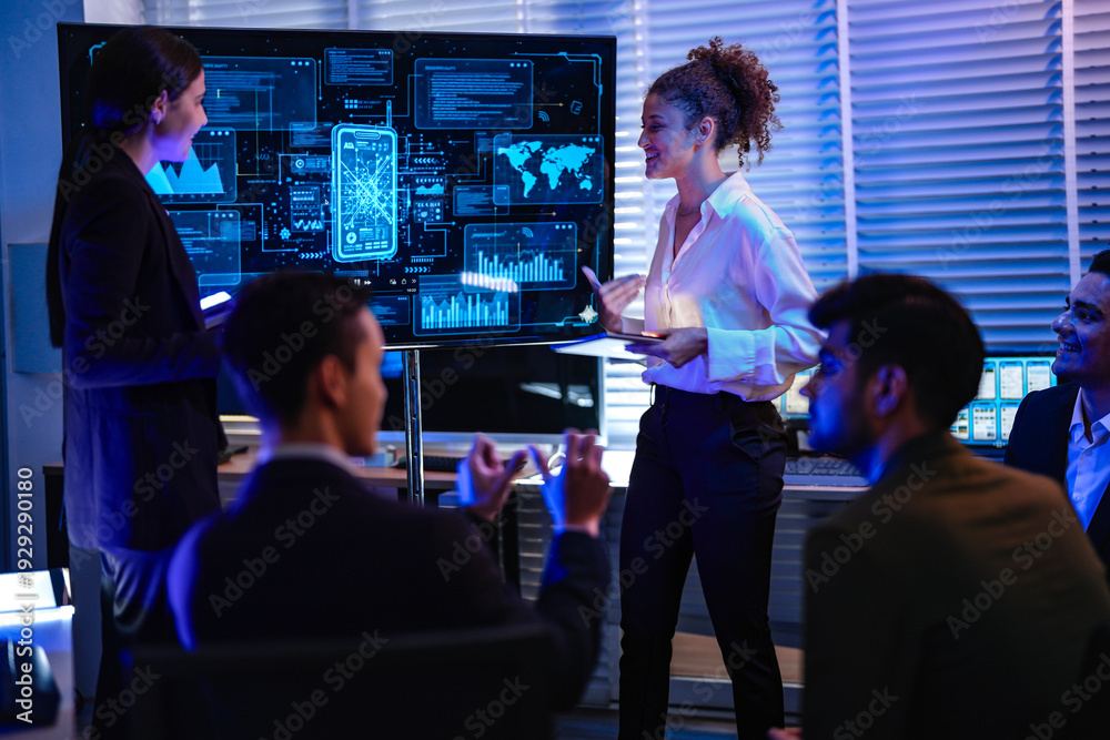 Obraz premium Professional IT team analyzing global network security dashboard in modern control center. Female manager leading cyber technology project discussion in dark night office.