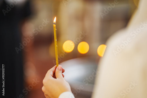 Holding a lit candle in a church during a religious service