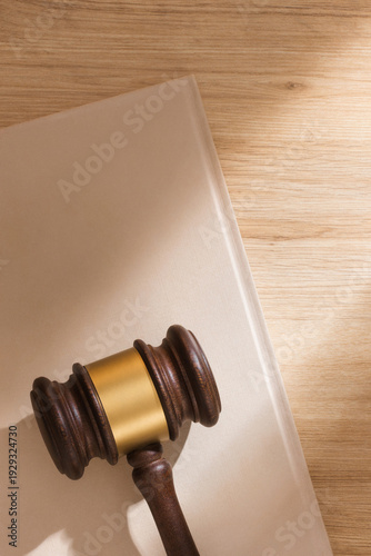 Konstfotografi A judge's gavel on beige notebook and light wooden background in soft sunlight