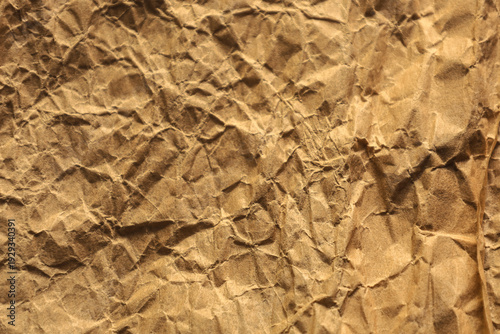 Textured background made of brown craft paper with a dense network of small wrinkles and uneven creases. The detailed surface of the material creates a pronounced effect of antiquity, organicity, and 