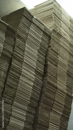 Massive stacks of corrugated cardboard sheets in a factory warehouse prepared for packaging production