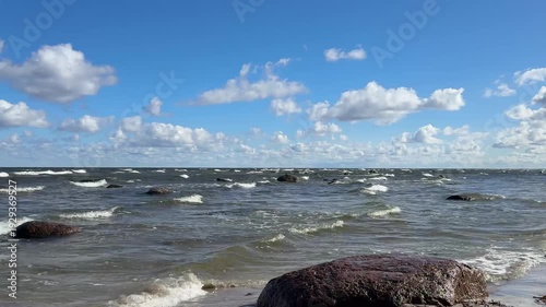 Rolling waves across shallow coastal water with scattered rocks. Natural sea sound recorded live. Detailed 4K beach footage.