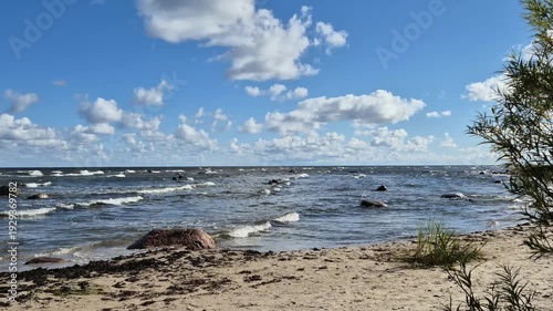 Sandy coastline with rolling waves and vibrant blue sky. Real natural sea sound recorded outdoors. High quality 4K beach video.