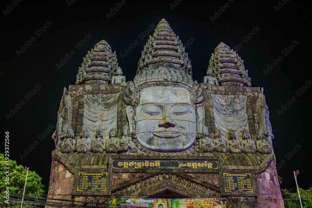 Obraz premium Illuminated Buddhist gate with stone faces at night in Siem Reap