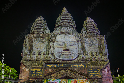Fotografija Illuminated Buddhist gate with stone faces at night in Siem Reap