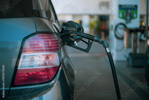 Primer plano de manguera de combustible surtiendo gasolina a un coche en una estación de servicio