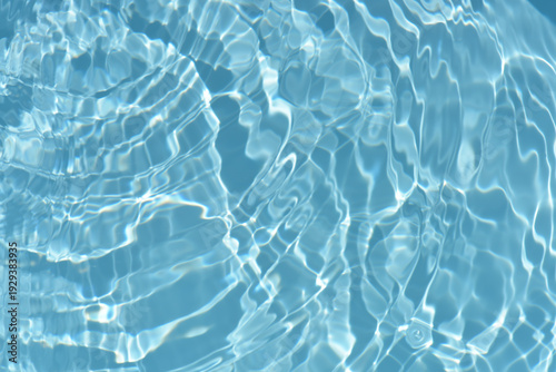 Blue water with ripples on the surface. Defocus blurred transparent blue colored clear calm water surface texture with splashes and bubbles. Water waves with shining pattern texture background.