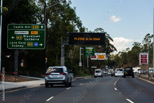 please slow down sign on overhead digital signage on road to castle hill A28