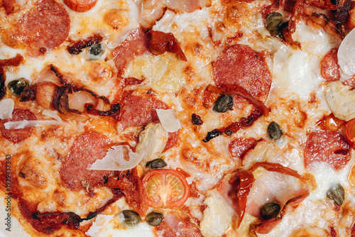 Close-up of pepperoni pizza with melted mozzarella, cherry tomatoes, capers and shaved parmesan