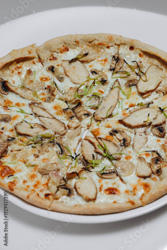 Wood-fired chicken and mushroom white pizza with melted cheese and scallions on a plate