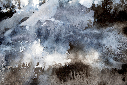 Abstract black and grey watercolour paint and ink swirling on white paper background to look like clouds and monochrome wash