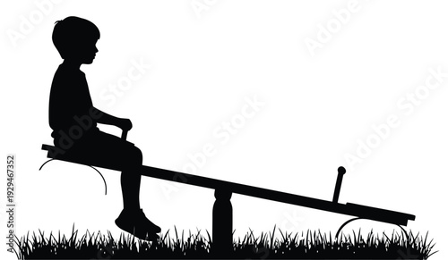 Silhouette of young boy playing alone on seesaw in grass