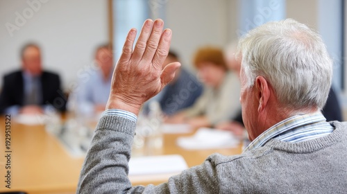 Senior man raising hand during town meeting. Community member participating in public discussion at municipal conference table