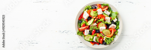 Greek salad of fresh cucumber, tomato, sweet pepper, lettuce, red onion, feta cheese and olives with olive oil. Healthy food. Top view