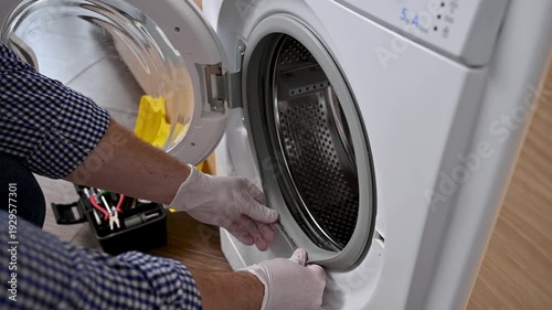 The person in white gloves checks the dirt on the rubber of a washing machine.