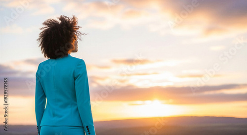 Black woman standing and looking at sunset over the horizon  