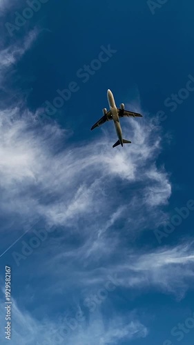 Passenger airplane ascent in blue sky with clouds low angle view
