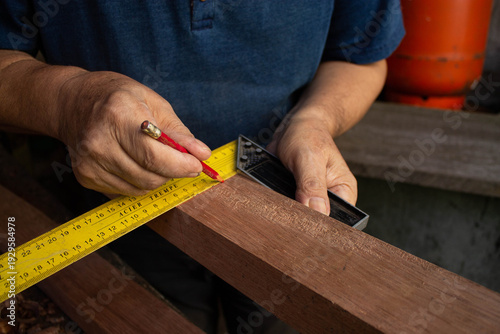 Foto Primer plano de manos de carpintero marcando madera con lápiz y escuadra amarilla