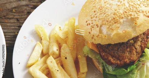 Displaying white plate with sesame-seed burger, peppered thick-cut fries on rustic table, overlays