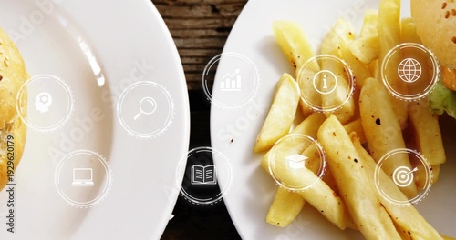 Displaying white plates with seasoned fries and burger buns, lettuce on dark table, digital icons