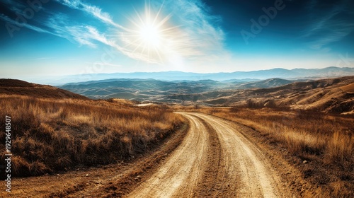 Winding dirt offroad trail through a breathtaking mountain landscape under bright sunlight