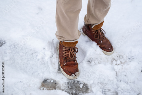 Foto Close-up man's boots walking on slippery snowy path, wet slush in winter suburbi