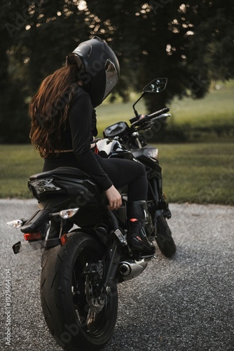 Female motorcyclist riding sport motorcycle at sunset outdoors