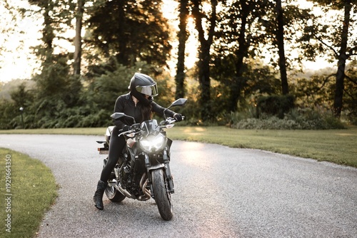 Female motorcyclist riding sport motorcycle at sunset outdoors