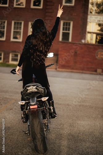 Female motorcyclist riding sport motorcycle at sunset outdoors