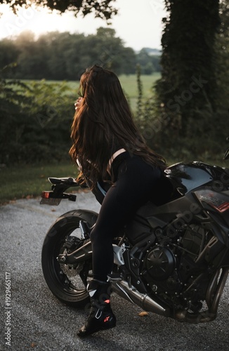 Female motorcyclist riding sport motorcycle at sunset outdoors