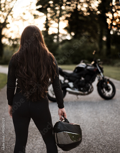 Female motorcyclist riding sport motorcycle at sunset outdoors