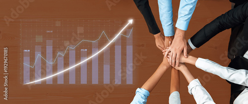 Fotografija Hands of diverse team members stacked together on table display unity while a growth graph in background symbolizes collective effort towards success and progress